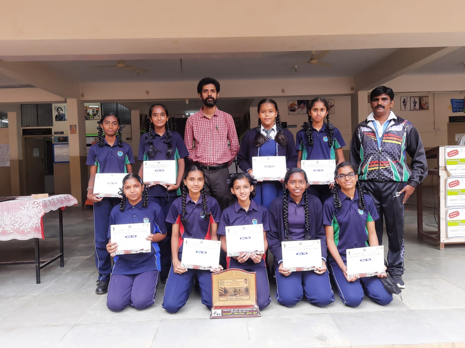 Girls’ volleyball team with certificates and a shield after the taluk-level competition
